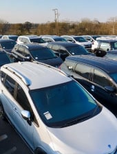 Banner sobre carros usados a crédito sin cuota inicial en Colombia, mostrando un inventario de vehículos en un lote de ventas.