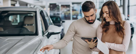 Banner sobre dónde comprar un carro usado en Colombia de forma segura, mostrando a una pareja revisando información en un concesionario.