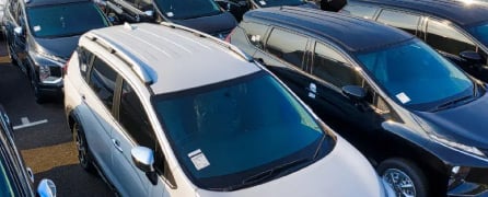 Banner de venta de vehículos usados sin cuota inicial, con vista aérea de un lote de camionetas y autos modernos